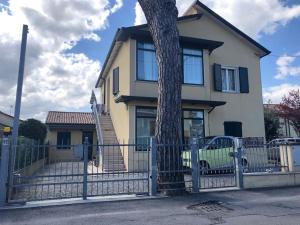 a house with a tree in front of a fence at SistersHome in Cervia