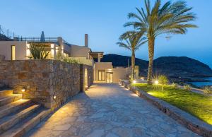 a pathway leading to a villa with a palm tree at Artisan's House in Sitia