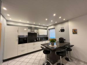 a kitchen with white cabinets and a table with black chairs at FEWO-Engelgrundweiher in Schmelz