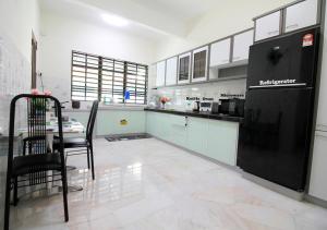 a kitchen with a table and a black refrigerator at H2H - Bintang49 Vacation House in Ipoh