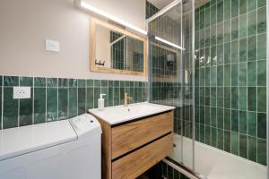 a green tiled bathroom with a sink and a washing machine at Vue sur le Palais - Nancy Gare Congrès - PARKING - T3 in Nancy