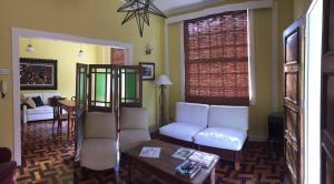 a living room with white chairs and a table at Casa Vila Brasil - Centro Histórico in Petrópolis