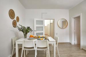 a white dining room with a white table and chairs at BBarcelona Encants Flat in Barcelona