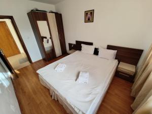 um quarto com uma cama branca com duas toalhas em Апартаменты в Belvedere em Bansko