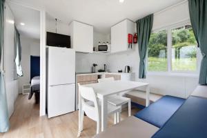 Camping Eurovil في بريدور: مطبخ وغرفة طعام مع طاولة وكراسي بيضاء