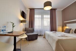 シュクラルスカ・ポレンバにあるWilla Na Cichejのベッド、テーブル、椅子が備わるホテルルームです。