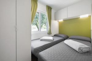 1 dormitorio con 2 camas y ventana en Camping Eurovil, en Predore