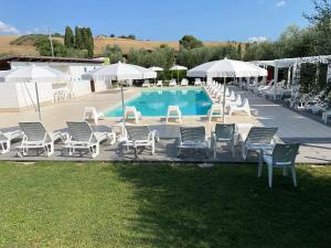 a group of chairs and umbrellas next to a pool at Agriturismo La Masseria - La casa tra gli alberi in Cugnoli