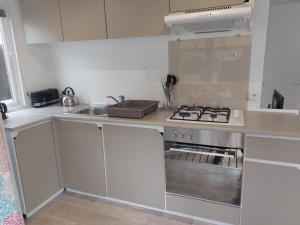 cocina con fogones y fregadero en Mobil home 7 couchages, en Ouistreham