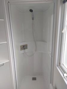 een douche in een witte badkamer met een douche bij Mobil home 7 couchages in Ouistreham