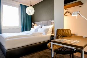 a bedroom with a bed and a desk and a chair at Motel One Nürnberg-City in Nuremberg