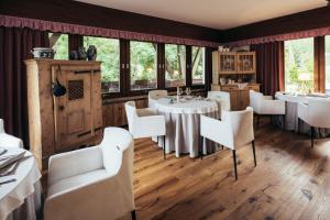 un restaurante con sillas blancas, mesas y ventanas en Haus Elisabeth en Santa Gertrude nella Val d'Ultimo