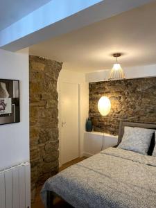 a bedroom with a bed and a stone wall at Le nuage des balmes in Caluire-et-Cuire
