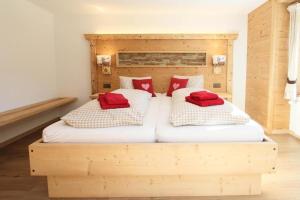 um quarto com uma cama de madeira e 2 almofadas vermelhas em Guggerzytch - "EIGER" - neue Ferienwohnung 2-4 Pers em Grindelwald