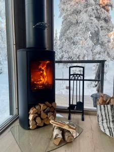 a fireplace in front of a window with a snow covered tree at WALD Villas - Aavasaksa, Lapland in Aavasaksa