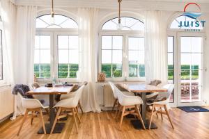 a dining room with two tables and chairs and windows at Pension Marie Luise 253 - Zimmer Meerschnecke in Juist