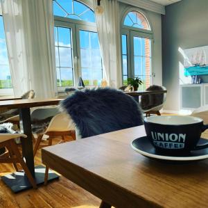 ein Zimmer mit einem Tisch und einer Kaffeetasse darauf in der Unterkunft Pension Marie Luise 253 - Zimmer Meerschnecke in Juist