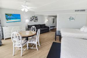 Una sala de estar con una cama, una mesa y sillas. en Vacation Time Oceanfront Deluxe Queen Room 4th Flr, en Pawleys Island