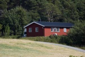 a red barn in the middle of a field at Strandstua Solbakken Feriehus in Fevåg