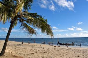 a group of people on a beach with a boat at The Frangipani Marari Beach in Mararikulam