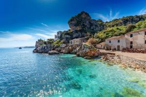 una spiaggia con acqua blu e case su una scogliera di BELVEDERE Appartamento per vacanze a Castel di Iudica