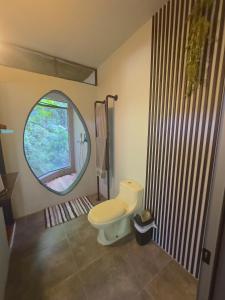 a bathroom with a toilet and a round mirror at Canaima Chill House in Santa Teresa Beach