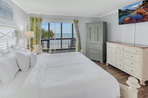 1 dormitorio con 1 cama blanca grande y balcón en Gorgeous Oceanfront 2 Bedroom Villa, en Pawleys Island