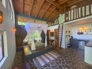 a bedroom with a bed with a canopy and a kitchen at Canaima Chill House in Santa Teresa Beach