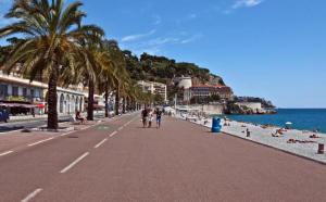 a beach with palm trees and people walking down a street at Florence in Nice