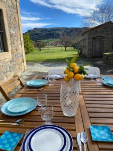 uma mesa de madeira com pratos e um vaso de frutas em LA QUINTA DE TUNTE em Villaviciosa