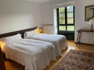 een slaapkamer met 2 bedden met witte lakens en een raam bij LA QUINTA DE TUNTE in Villaviciosa