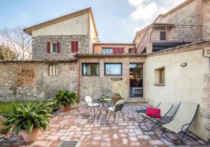 un patio con sillas y una mesa frente a un edificio en Lo Ziro - Agriturismo La Roverella, en Monteroni dʼArbia