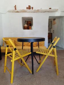 una mesa y dos sillas amarillas junto a un sofá en Casa Trullo Bianco: Casa Limone, en Ceglie Messapica