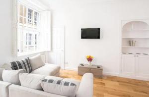a white living room with a white couch and a tv at Orchard Street: 1BR with Garden in Bath