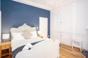 a bedroom with a white bed with a blue wall at Orchard Street: 1BR with Garden in Bath