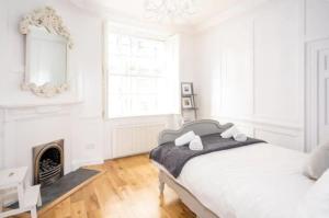 Dormitorio blanco con cama y chimenea en Orchard Street: 1BR with Garden en Bath