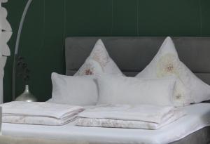 a bed with white pillows and a green wall at Prinz Ole in Haan