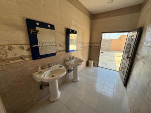 baño con 2 lavabos y ventana en شاليه مجهز بالكامل مسبح وملعب و حديقه هادئه بضباء, en Ḑubā