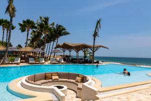 a man in a swimming pool next to the ocean at Punta Sal Suites & Bungalows Resort in Canoas De Punta Sal