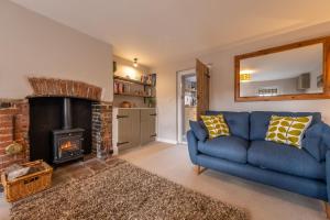 a living room with a blue couch and a fireplace at Wishing Well Cottage in North Creake