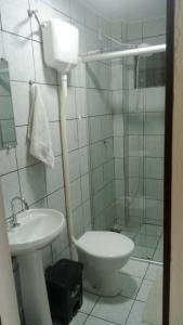 a bathroom with a sink and a toilet and a shower at Apto 03 - 1 quarto com 2 camas solteiro e garagem, possui ventilador de teto in Cascavel