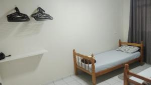 a small bed in a room with shoes on the wall at Apto 03 - 1 quarto com 2 camas solteiro e garagem, possui ventilador de teto in Cascavel