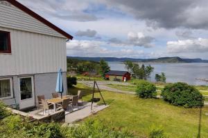 a house with a table and chairs and a view of the water at Apartment Solbakken Feriehus in Fevåg