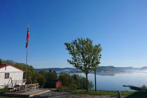 vistas a un lago con una casa y una bandera en Apartment Solbakken Feriehus, en Fevåg