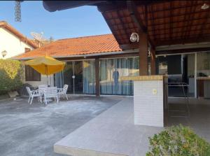 eine Terrasse mit einem Tisch und einem gelben Sonnenschirm in der Unterkunft Paraíso no Sudoeste in São Pedro da Aldeia