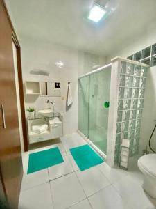 uma casa de banho com um chuveiro e um WC com tapetes azuis em Paraíso no Sudoeste em São Pedro da Aldeia