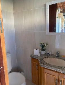 uma casa de banho com um WC, um lavatório e um espelho. em Paraíso no Sudoeste em São Pedro da Aldeia