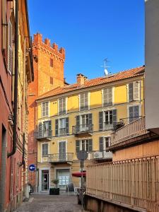 un bâtiment jaune avec balcon et un bâtiment en briques dans l'établissement Il Bumbunin Esclusivo monolocale nel cuore di Asti, à Asti
