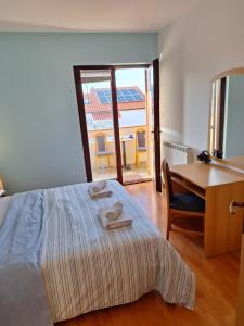 een slaapkamer met een bed, een bureau en een tafel bij Apartmani Vuković Punat in Punat