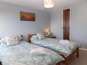 a bedroom with two beds and a table with a lamp at Dairy Cottage in South Molton